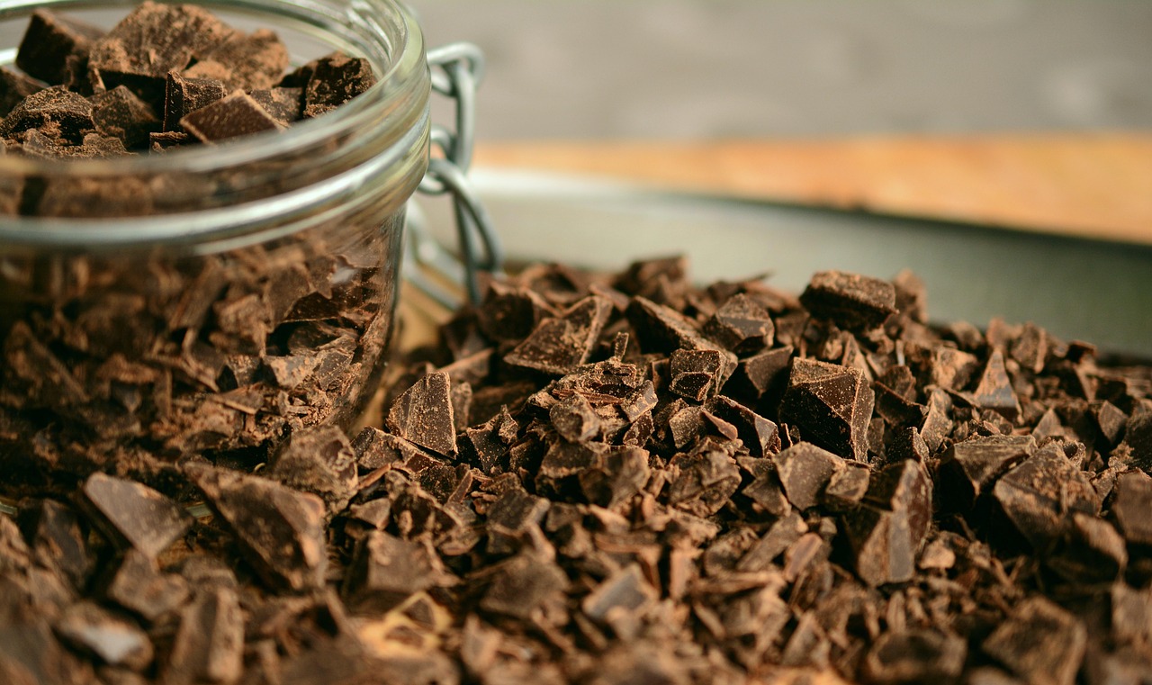 Chunks and pieces of dark chocolate overflowing from a jar