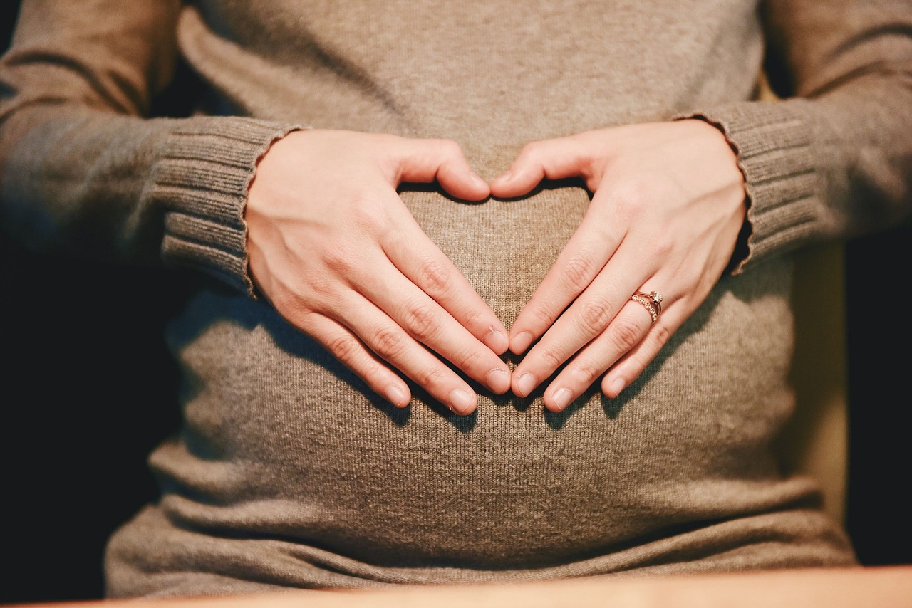 woman with hands in shape of heart across baby belly bump