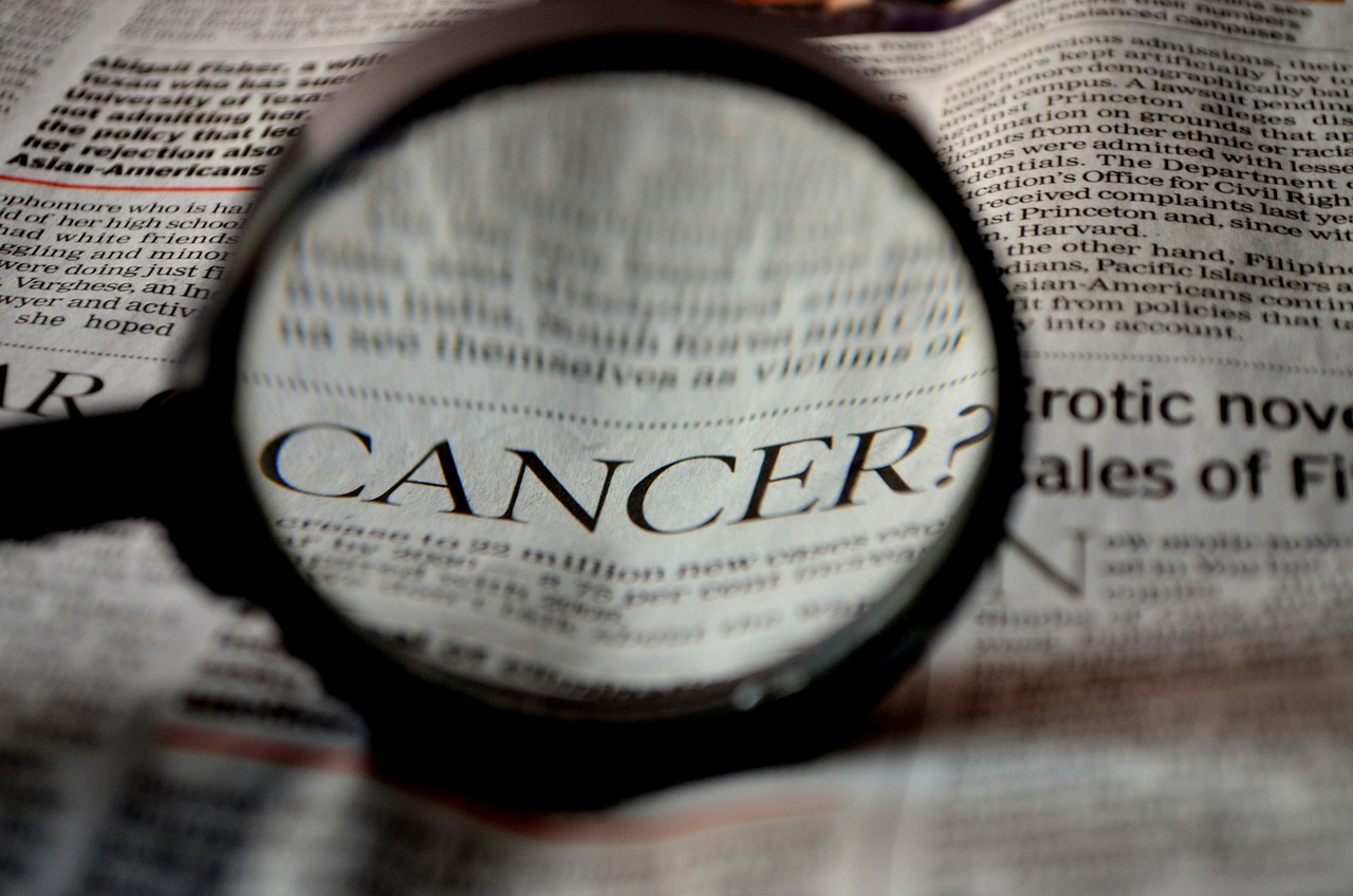 975 A new treatment for Pancreatic cancer magnifying glass over word CANCER in newspaper